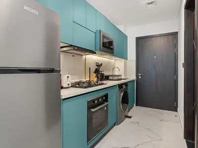 a kitchen with blue cabinets and a refrigerator at Opalz Solace Cozy Luxe Studio 03 in Dubai