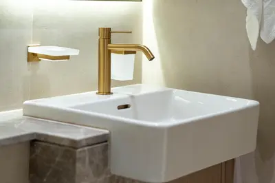 a white sink with a gold faucet in a bathroom at The Royal Blue Jacuzzi Suite 32 1-6-10 I JVC I Dar Oasis in Dubai