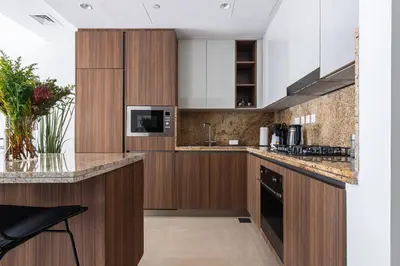 a kitchen with wooden cabinets and a counter top at Downtown Dubai - Bright 1BR Apartment - Imperial Avenue in Dubai