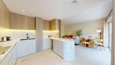a kitchen with white cabinets and a dining room at Vacationer l Opulent 2 Bedroom Villa l Private Plunge Pool in Dubai