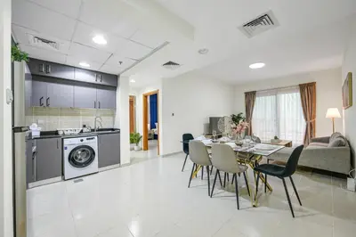 a kitchen and living room with a table and chairs at Spacious 1BR Magnolia 1 JVC in Dubai