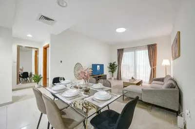 a living room with a table and a couch at Spacious 1BR Magnolia 1 JVC in Dubai
