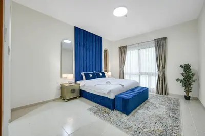 a bedroom with a blue bed and a window at Spacious 1BR Magnolia 1 JVC in Dubai