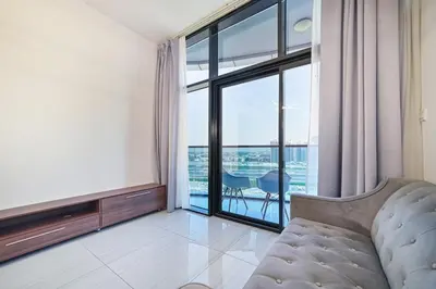 a living room with a couch and a large window at Balcony Breeze O2 with amazing high way view in Dubai