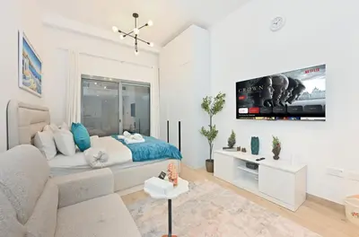 a white room with a bed and a tv on the wall at Bloomfields Comfort Studio at Bali Residence, DXB in Dubai