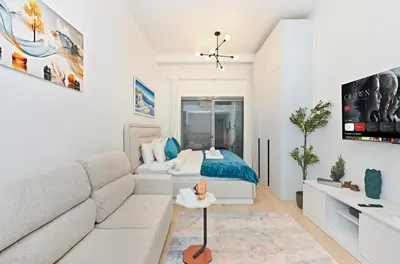 a white living room with a couch and a bed at Bloomfields Comfort Studio at Bali Residence, DXB in Dubai