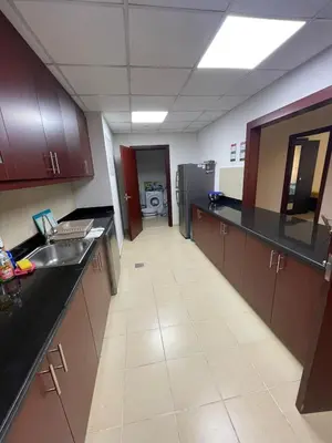a large kitchen with black counter tops and a refrigerator at Two Bedroom Apartment with Excellent Location in Dubai