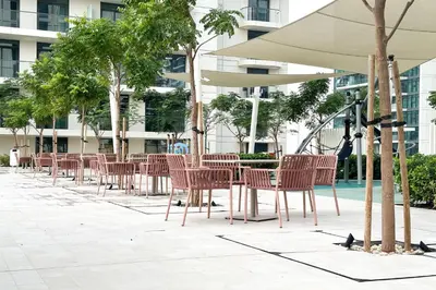 a row of chairs and tables in front of a building at Sea View Apartment at Emaar Beachfront by KeyRock in Dubai