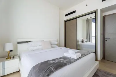 a white bedroom with a large bed and a mirror at GuestReady- Comfortable 1 bedroom- High Floor in Dubai