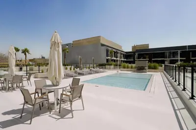 a patio with a table and chairs and a pool at GuestReady- Comfortable 1 bedroom- High Floor in Dubai
