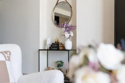 a living room with a mirror and a table with flowers at Stylish 1BR, Walk to Burj Khalifa and Dubai Mall in Dubai