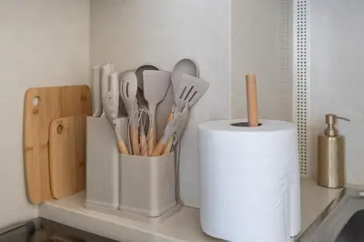 a counter with a container of utensils and a roll of paper towels at Stylish 1BR, Walk to Burj Khalifa and Dubai Mall in Dubai