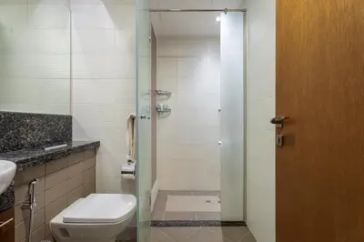 a bathroom with a toilet and a glass shower door at GuestReady | Studio | Partial Burj Khalifa View in Dubai