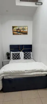 a bed with a blue headboard in a bedroom at Bienvenue Homes in Dubai