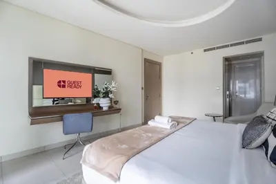 a white bedroom with a bed and a tv at GuestReady - Chic Damac Paramount | Business Bay in Dubai