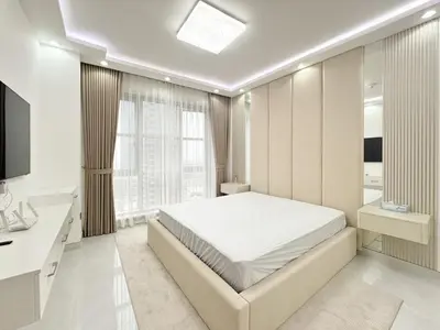 a white bedroom with a bed and a television at Dream Shoma-2BR - Pool - Walk to Burj Khalifa in Dubai