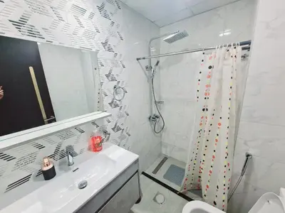 a white bathroom with a shower and a sink at Fully Equipped Home near Miracle & Butterfly Gardens in Dubai