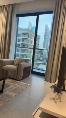 a living room with a couch and a large window at Modern Downtown 1BR Apartment in jumeirah Garden in Dubai