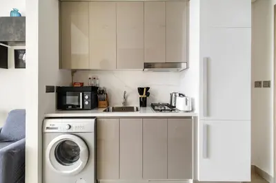 a kitchen with a washing machine and a microwave at Chic Studio in Azizi Riviera Minutes to Downtown in Dubai