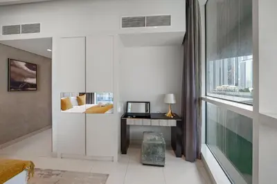 a bedroom with a bed and a desk and a window at Nice 2 Bedroom DAMAC Uppercrest Downtown Near Dubai Mall - Partial Burj Khalifa View in Dubai