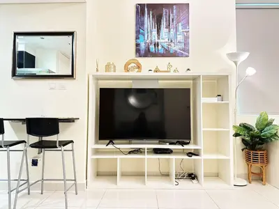 a living room with a television on a white wall at Modern Studio in Executive Bay Business Bay Pool, Gym with WiFi in Dubai