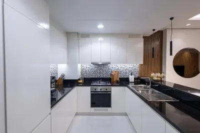 a kitchen with white cabinets and black counter tops at Top Amenities, Luxury 2BR, 5 min. to Burj Khalifa in Dubai