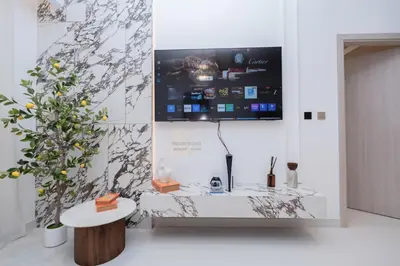 a living room with a tv on a wall at Luxurious chic getaway for 4, pool view, hammam, sauna, PS5 in Dubai