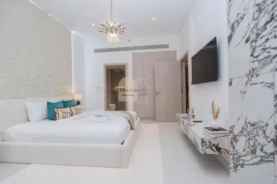 a white bedroom with a white bed and a chandelier at Luxurious chic getaway for 4, pool view, hammam, sauna, PS5 in Dubai