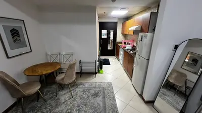a kitchen with a table and chairs and a refrigerator at Dream home in Dubai