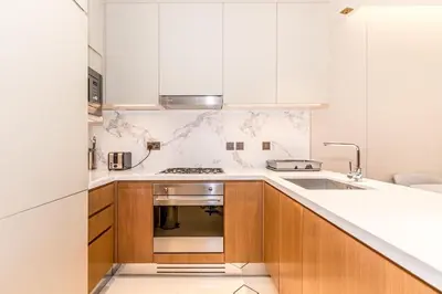 a kitchen with white cabinets and a stove top oven at 3BR with Full Burj Khalifa and Dubai Fountain View at Address Opera in Dubai