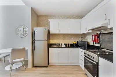 a kitchen with white cabinets and a refrigerator at Modern 1BR Unit Close to Canal Walk & Burj Khalifa in Dubai