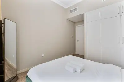 a bedroom with a white bed and a mirror at Modern 1BR Unit Close to Canal Walk & Burj Khalifa in Dubai