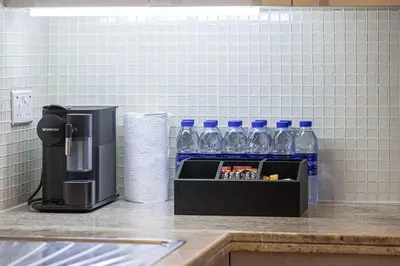 a counter with a coffee maker and bottles of water at Boulevard Chic Modern 2BR with Iconic Street Views in Dubai
