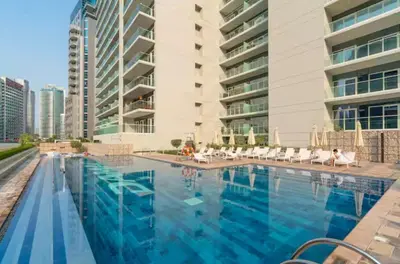 a large swimming pool in front of a building at Elegant 2BR Business Bay Canal View Gym & Pool in Dubai