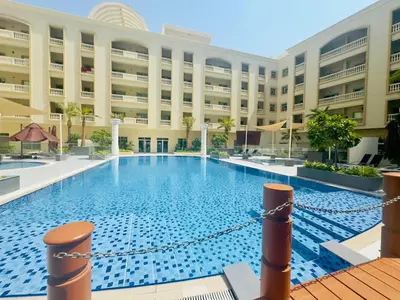 a large swimming pool in front of a building at Stylish Furnsihed Apartments Opposite Five Hotel In JVC in Dubai
