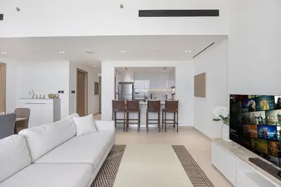 a living room with a white couch and a kitchen at Daniels Chic 1BR with City Skyline Views at JVC in Dubai
