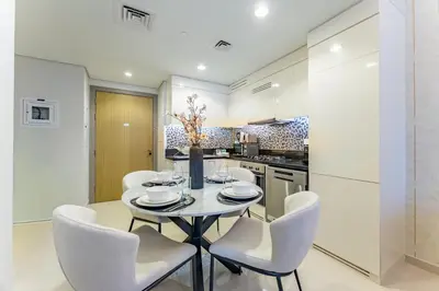 a white kitchen with a table and chairs at Near Safa Park, Offering Easy Access to Downtown Dubai, Jumeirah Beach and Kite Beach - Aykon City 2 Tower C, Business Bay by Deluxe Holiday Homes in Dubai
