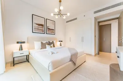 a white bedroom with a white bed and a chandelier at Just Moments from Coca-Cola Arena and Metro 1BR, Surrounded by a Vibrant Array of Retail and Dining Outlets, Viridian, Al Wasl by Deluxe Holiday Homes in Dubai