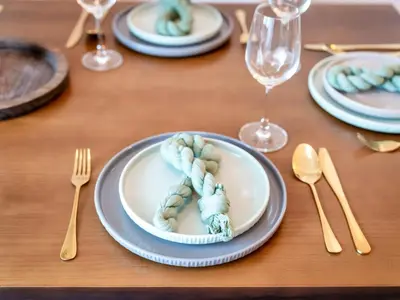 a wooden table with plates and forks and glasses at Ultra Stylish Luxury Flat w Harbour View in Dubai Marina, Sleeps 10 pax in Dubai