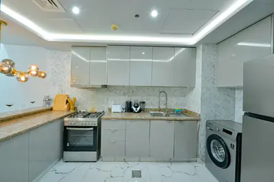 a kitchen with white cabinets and a stove top oven at Luxestay Holiday Homes in Dubai