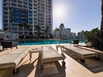 a swimming pool with benches in front of a building at Luxury Waterfront Studio - Stunning Canal Views in Damac Maison Prive in Dubai
