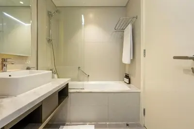 a white bathroom with a tub and a sink at Luxury Waterfront Studio - Stunning Canal Views in Damac Maison Prive in Dubai