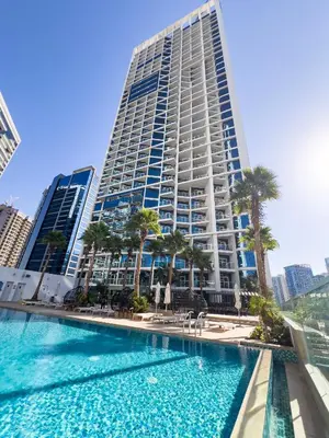 a large building with palm trees and a swimming pool at Luxury Waterfront Studio - Stunning Canal Views in Damac Maison Prive in Dubai