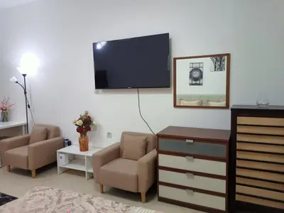 a living room with a tv and a couch and chairs at Dubai Marina Studio in Dubai