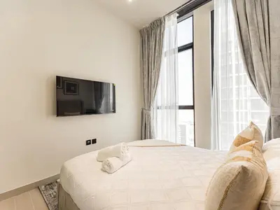 a bedroom with two beds and a tv on the wall at Brand New High Floor 1 BR with city view, pool and gym in Dubai