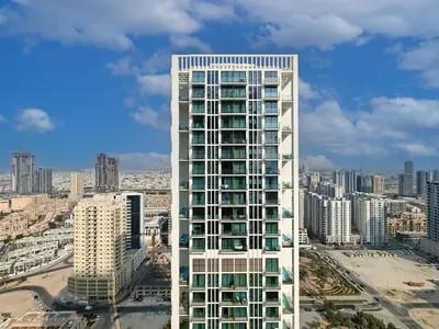 a tall white building in front of a city at Brand New High Floor 1 BR with city view, pool and gym in Dubai