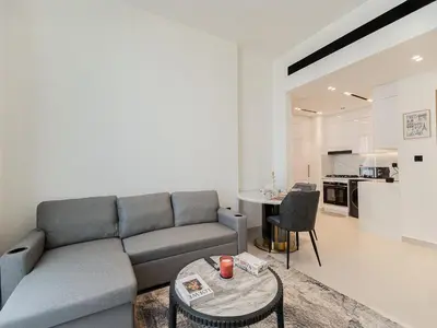 a living room with a couch and a table at Brand New High Floor 1 BR with city view, pool and gym in Dubai