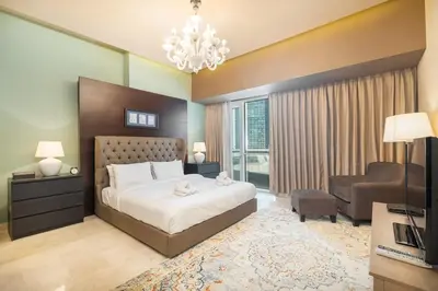 a bedroom with a large bed and a living room at StayShort - Majestic 4BR in Dubai Marina - Sleeps 8 in Dubai