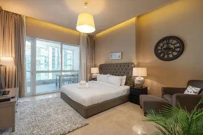 a bedroom with a bed and a chair and a clock at StayShort - Majestic 4BR in Dubai Marina - Sleeps 8 in Dubai