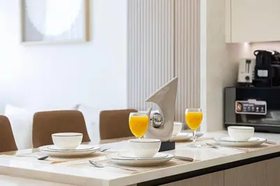 a table with two cups and two glasses of orange juice at Luxury Binghatti Phantom Suites By Hostiva in Dubai